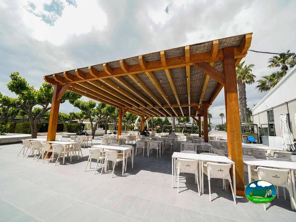 Restaurante bar con pérgola de madera y vistas al jardín del Camping Platja Cambrils, Cambrils (Tarragona)