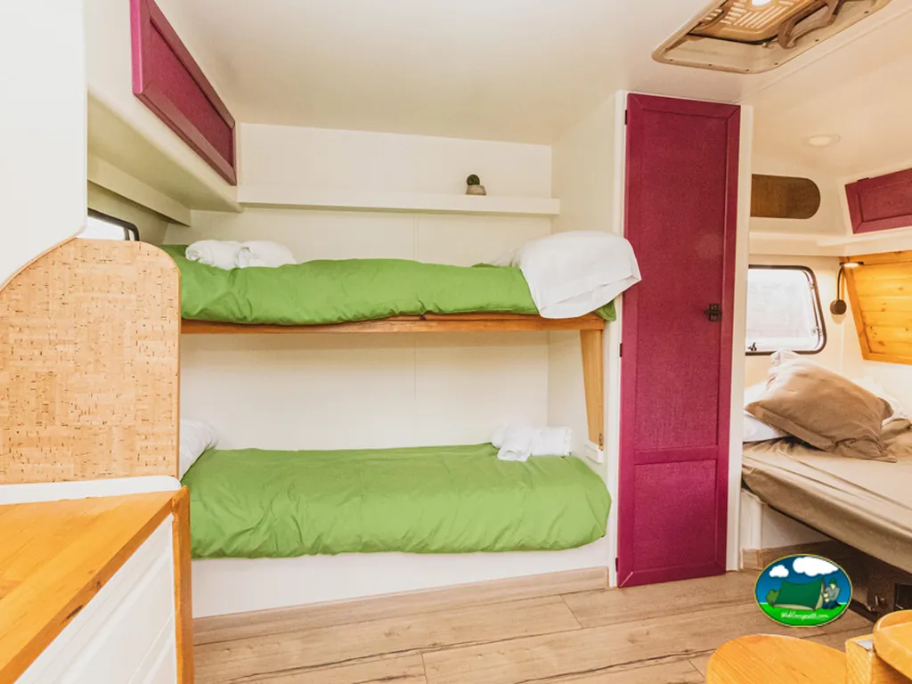 Mobil-home interior con literas y ropa de cama verde del Camping Ecocamp Vinyols, Vinyols i els Arcs (Tarragona)