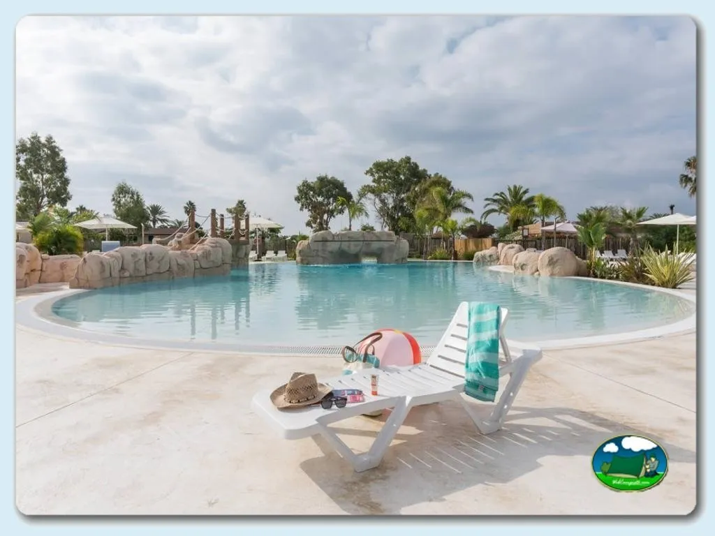 Piscina con vistas a palmeras y sombrillas del Camping Caravaning Gavina, Creixell (Tarragona)