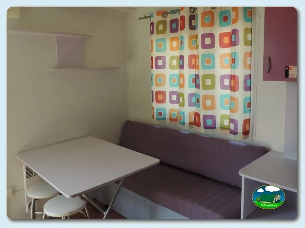 Mobil-home interior con zona de estar y cortinas decorativas del Camping El Carlitos, Arenys de Mar (Barcelona)