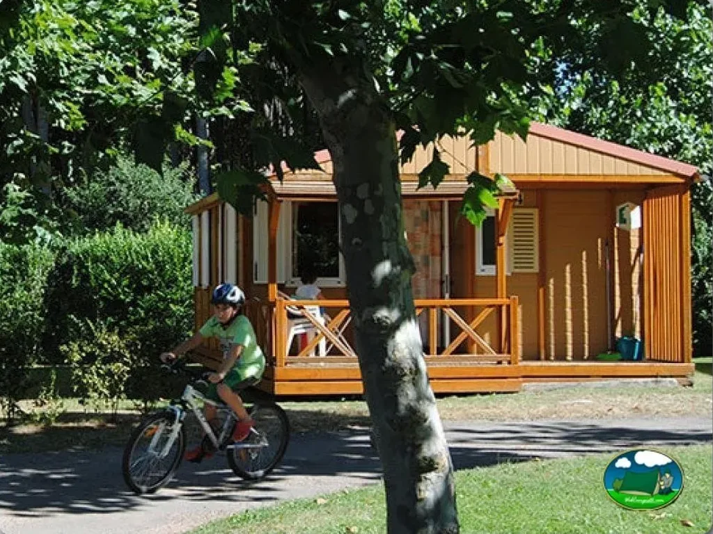 Mobil-home de madera con ciclista en parcela arbolada del Camping Berceo, Berceo (La Rioja)