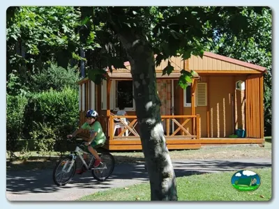 Mobil-home de madera con ciclista en parcela arbolada del Camping Berceo, Berceo (La Rioja)