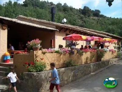 Restaurante con terraza y sombrillas rojas, montaña al fondo del Camping El Puente, Rodellar (Huesca)
