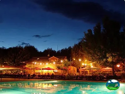 Piscina climatizada nocturna con restaurante y bar iluminado del Camping Canfranc, Canfranc (Huesca)