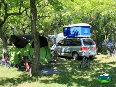 Parcela arbolada con tienda de acampada y vehículo del Camping Peña Montañesa, Labuerda (Huesca)