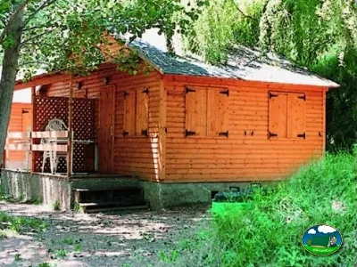 Cabaña de madera roja entre árboles del Camping Peña Montañesa, Labuerda (Huesca)