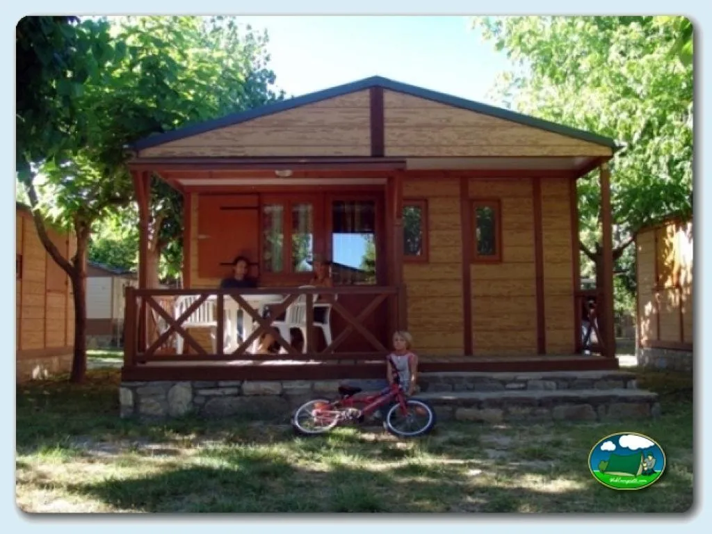 Bungalow de madera con terraza y sombrilla del Camping Peña Montañesa, Labuerda (Huesca)
