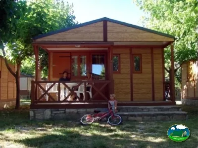 Bungalow de madera con terraza y sombrilla del Camping Peña Montañesa, Labuerda (Huesca)