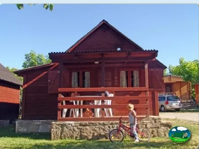 Cabaña de madera roja con terraza y zona infantil del Camping Peña Montañesa, Labuerda (Huesca)