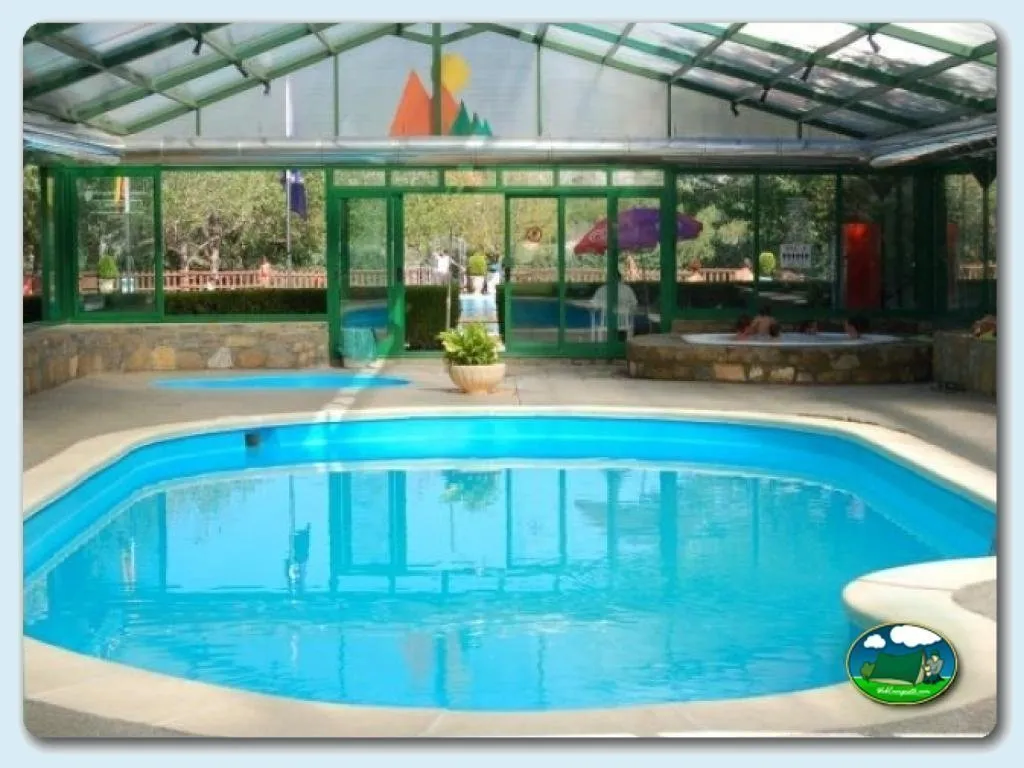 Piscina climatizada cubierta con vistas al parque infantil del Camping Peña Montañesa, Labuerda (Huesca)