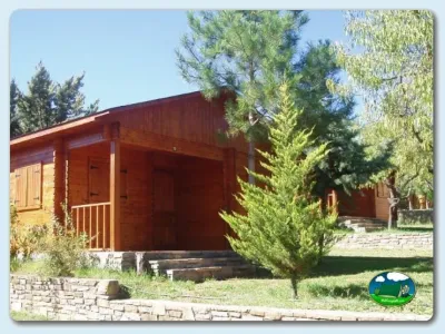 Cabaña de madera roja en parcela arbolada del Camping Lago Barasona, La Puebla de Castro (Huesca)