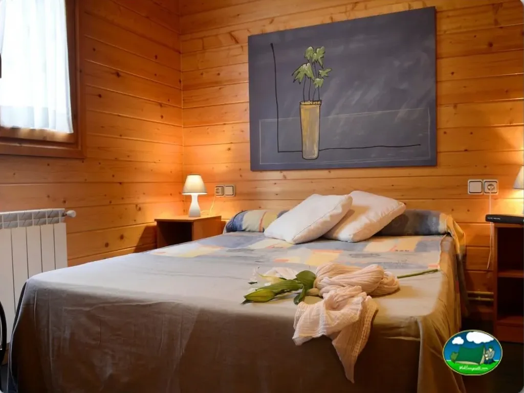 Cabaña interior con cama doble y paredes de madera del Camping Baliera, Bonansa (Huesca)