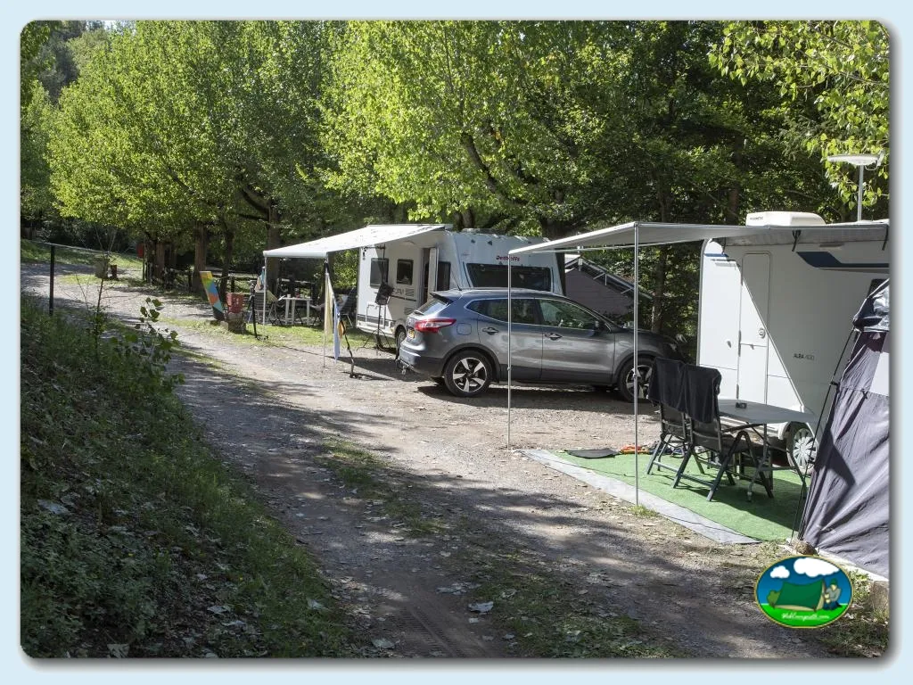 Parcela con mobil-home y autocaravana entre árboles del Camping Alta Ribagorça, Las Bordes del Pont de Suert (Lleida)