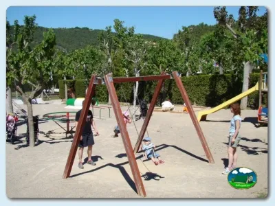 Parque infantil con columpios y tobogán, rodeado de árboles del Camping El Solsonés, Solsona (Lleida)