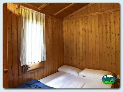 Cabaña interior con cama doble y ventana del Camping El Solsonés, Solsona (Lleida)