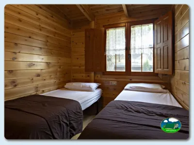 Cabaña de madera con dos camas y ventanas del Camping El Solsonés, Solsona (Lleida)