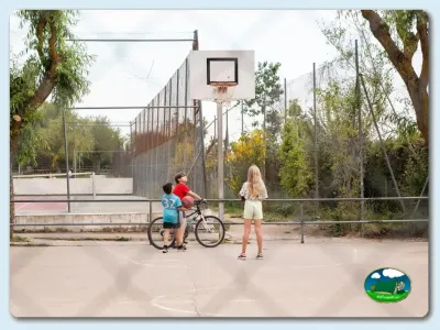 Parque infantil con cancha de baloncesto y niños en bicicleta del Camping El Solsonés, Solsona (Lleida)
