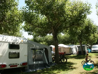 Parcela con caravana y árboles frondosos del Camping Laspaúles, Castejón de Sos (Huesca)