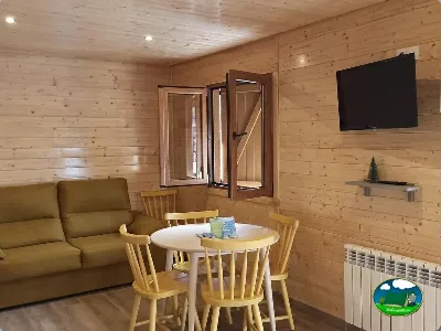 Glamping interior con salón de madera, sofá y zona de comedor del Camping Laspaúles, Castejón de Sos (Huesca)
