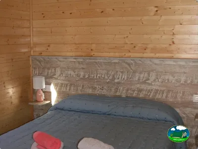 Cabaña interior con cama doble y cabecero de madera del Camping Laspaúles, Castejón de Sos (Huesca)