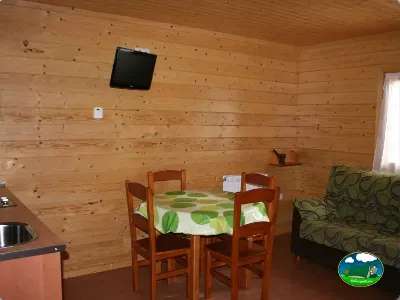 Cabaña interior con mesa de madera y sofá del Camping Laspaúles, Castejón de Sos (Huesca)