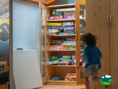Parque infantil interior con niño y estantería de juegos de mesa del Camping Laspaúles, Castejón de Sos (Huesca)