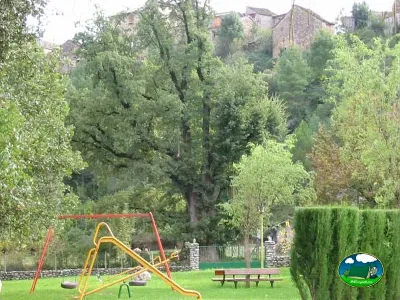 Parque infantil con columpios y tobogán en zona arbolada del Camping Valle de Añisclo, Puyarruego (Huesca)