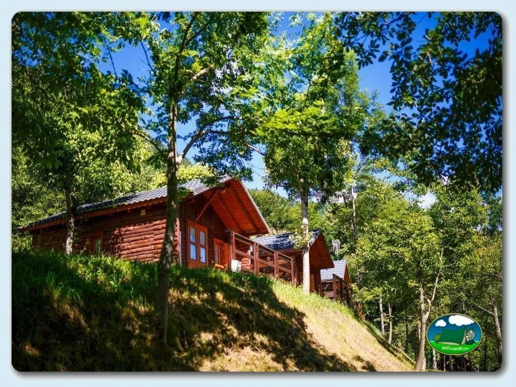 Cabaña de madera roja en la montaña rodeada de árboles del Camping Bedura Park, Val D'Aran (Lleida)