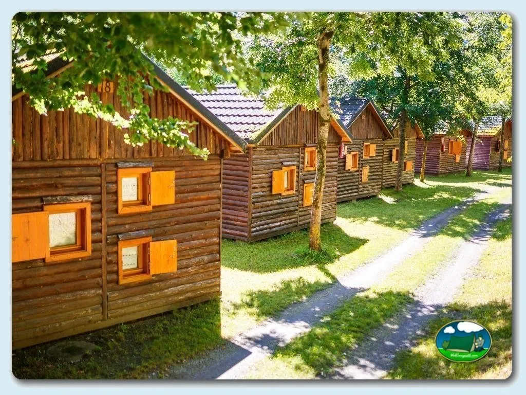 Cabaña de madera con ventanas naranjas en parcela arbolada del Camping Bedura Park, Val D'Aran (Lleida)