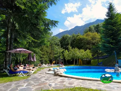 Piscina con vistas a la montaña y sombrillas del Camping Bedura Park, Val D'Aran (Lleida)