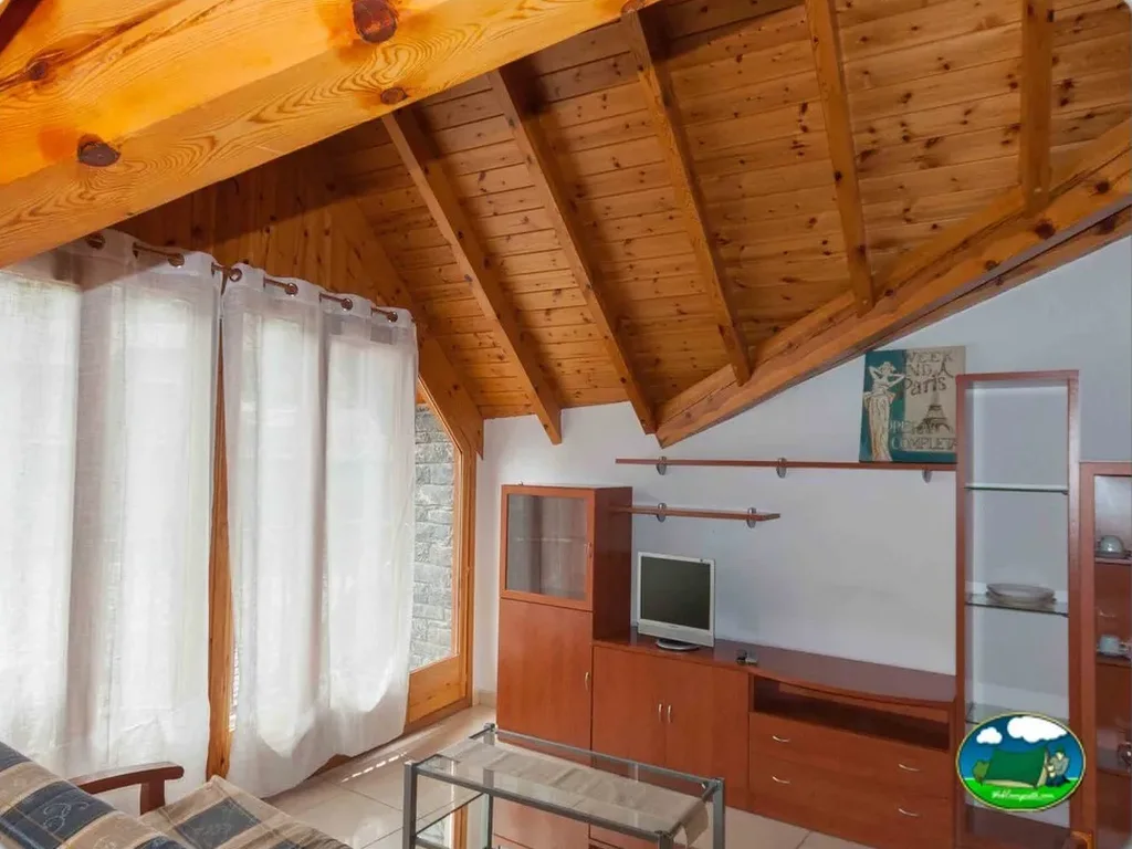 Cabaña interior con vigas de madera y estar del Camping Vall Ferrera, Alins (Lleida)
