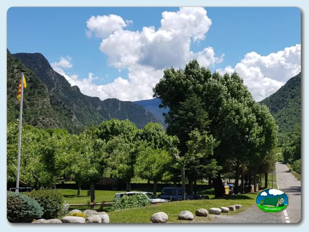 Parcela con vistas a la montaña, árboles y cielo despejado del Camping Cardós, Cardós Pirineus (Lleida)