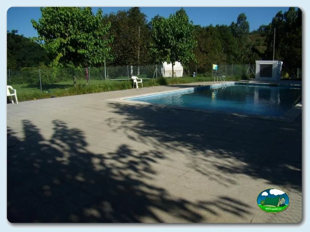 Piscina con zona de sombrilla y entorno arbolado del Camping La Balma, Espinelves (Girona)