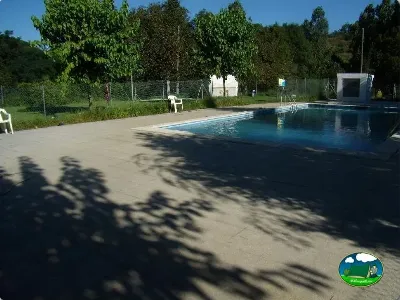 Piscina con zona de sombrilla y entorno arbolado del Camping La Balma, Espinelves (Girona)