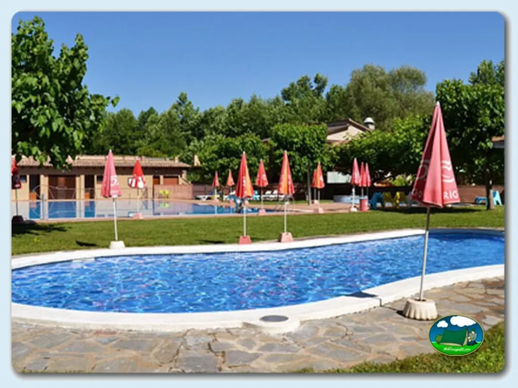 Piscina con sombrillas rojas y césped del Camping L'Alguer, Les Planes d`Hostoles (Girona)