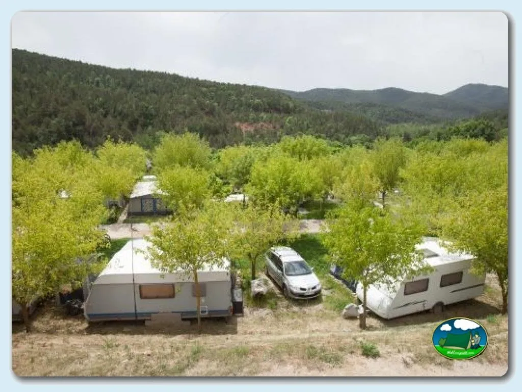 Parcelas con mobil-homes rodeadas de árboles y montaña al fondo del Camping Campalans, Borreda (Barcelona)