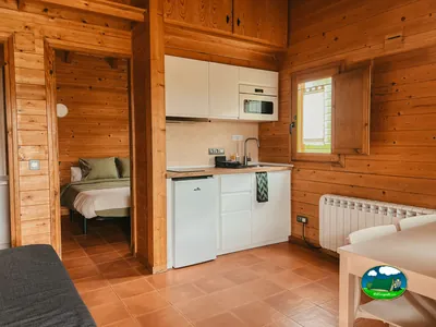 Cabaña interior con cocina, dormitorio y zona de estar del Camping Campalans, Borreda (Barcelona)