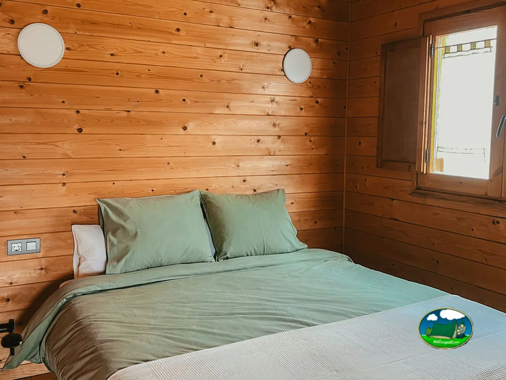 Cabaña interior con cama y paredes de madera del Camping Campalans, Borreda (Barcelona)