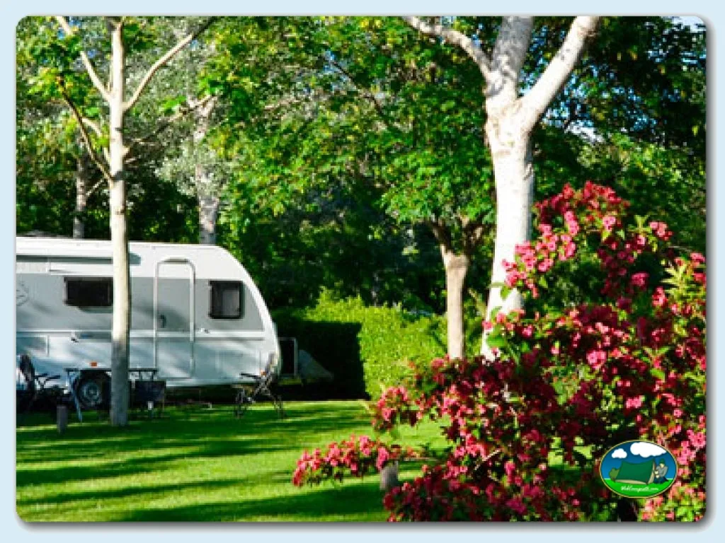 Parcela con mobil-home entre árboles y flores del Camping Montagut, Montagut i Oix· Girona (Girona)