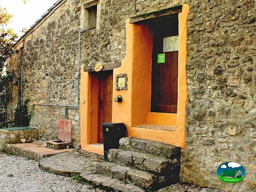 Cabaña de piedra con entrada amarilla del Camping Masia Sadernes, Sadernes (Girona)