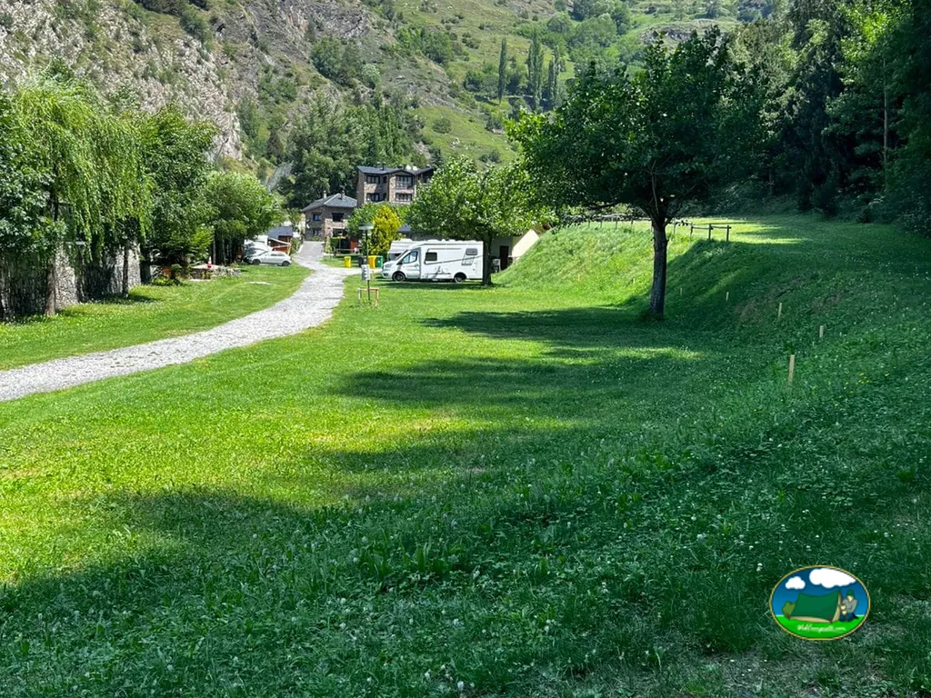 Parcelas de césped con una autocaravana y montañas en el Camping Jan Ramon de Canillo
