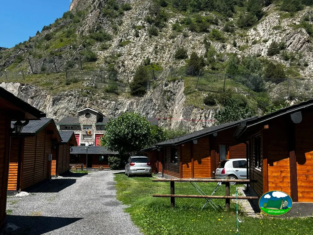 Camino entre cabañas de madera con montañas en el Camping Jan Ramon de Canillo
