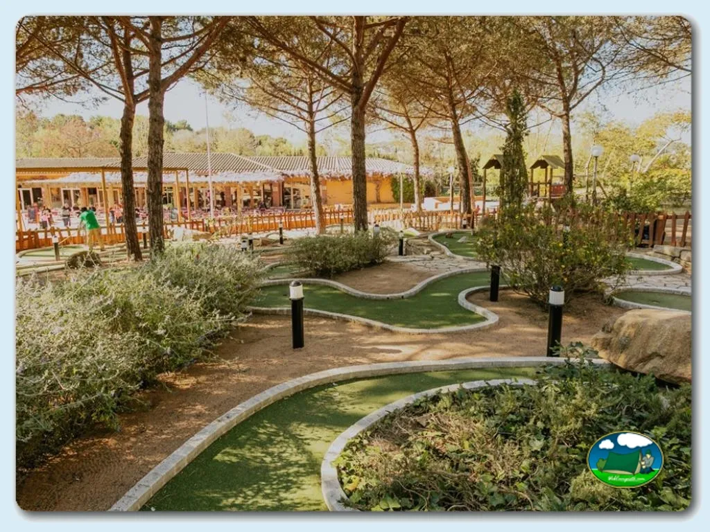 Parque infantil con minigolf bajo árboles del Camping Santa Elena Ciutat, Lloret de Mar (Girona)