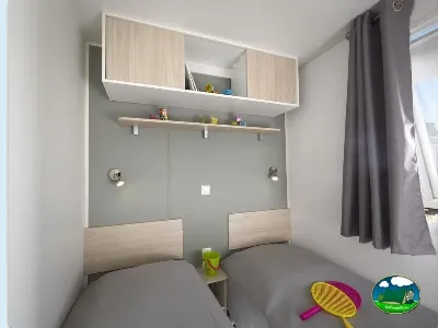 Mobil-home interior con dos camas y espejo del Camping Lloret Blau, Lloret de Mar (Girona)
