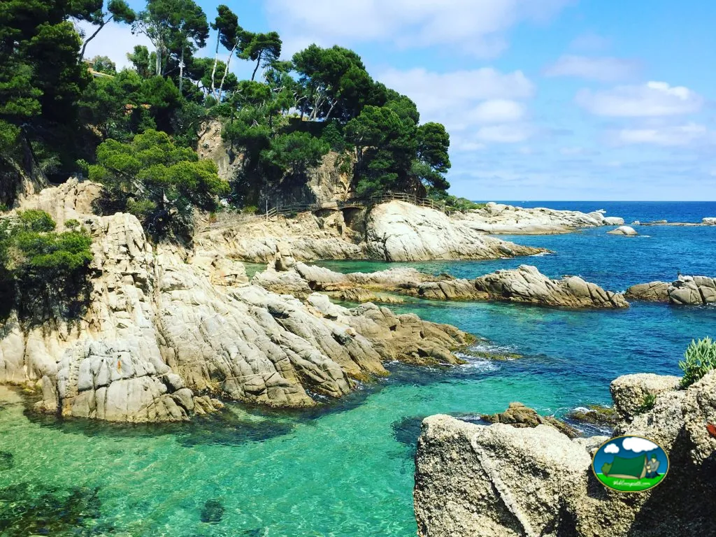 Playa junto al mar con acantilado rocoso y aguas turquesas del Camping Internacional de Calonge, Calonge (Girona)