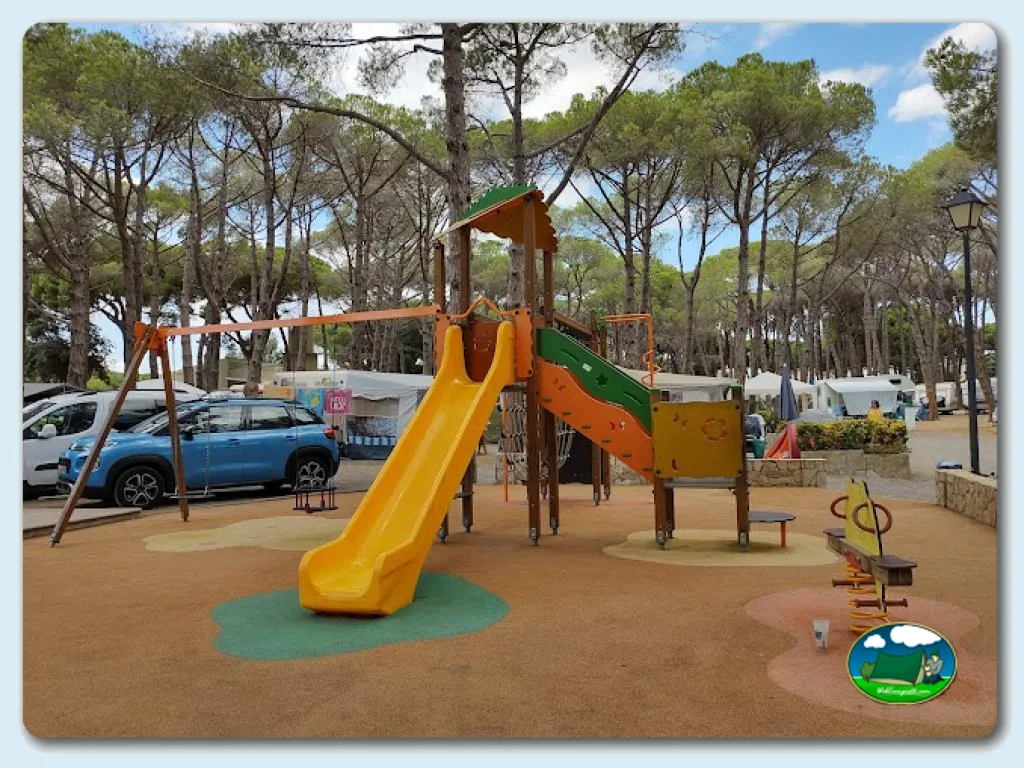 Parque infantil con tobogán amarillo entre pinos del Camping Costa Brava, Sant Antoni de Calonge (Girona)