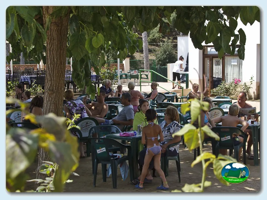 Restaurante bar con zona de comedor al aire libre entre árboles del Camping Benelux, Palamos (Girona)