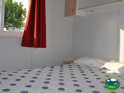 Mobil-home interior con cama y ventana del Camping Mas Patoxas, Pals (Girona)