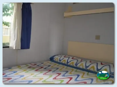 Mobil-home interior con cama y ventana del Camping Mas Patoxas, Pals (Girona)