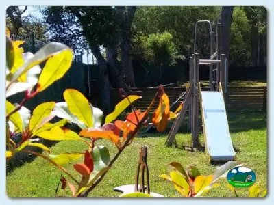 Parque infantil junto al río con tobogán y flores del Camping Mobydick, Calella de Palafrugell (Girona)